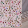 A close-up of a light pink watercolor printed scarf featuring green and pink floral vines.