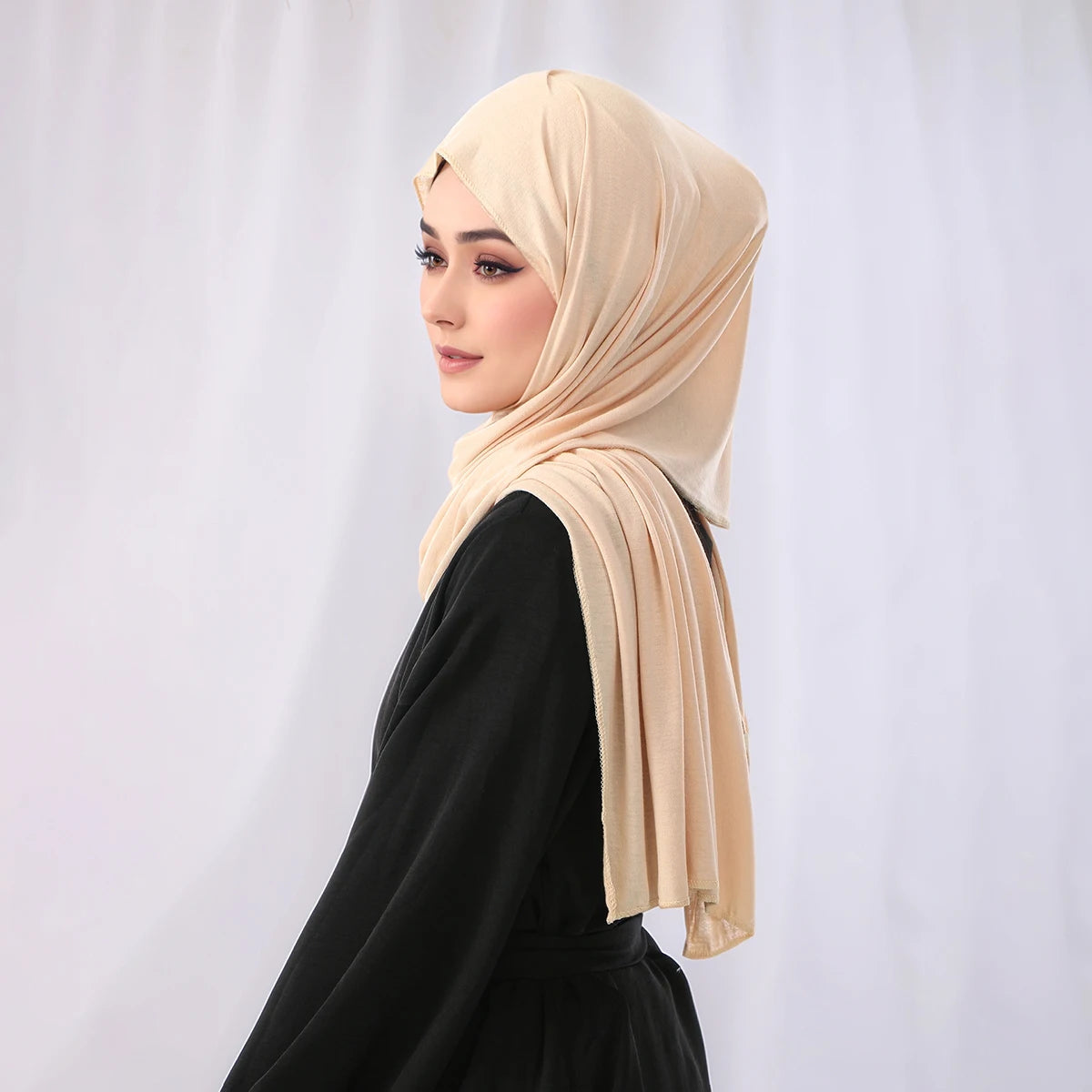 Eine Frau trägt ein elegantes beige Modal-Jersey-Hijab mit einem schwarzen Oberteil.