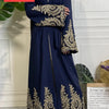 Una lujosa caftán abaya azul oscuro para mujeres con bordados dorados en las mangas y el dobladillo.