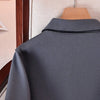 Vue arrière d'un manteau à boutons en laine gris anthracite sur un cintre en bois.