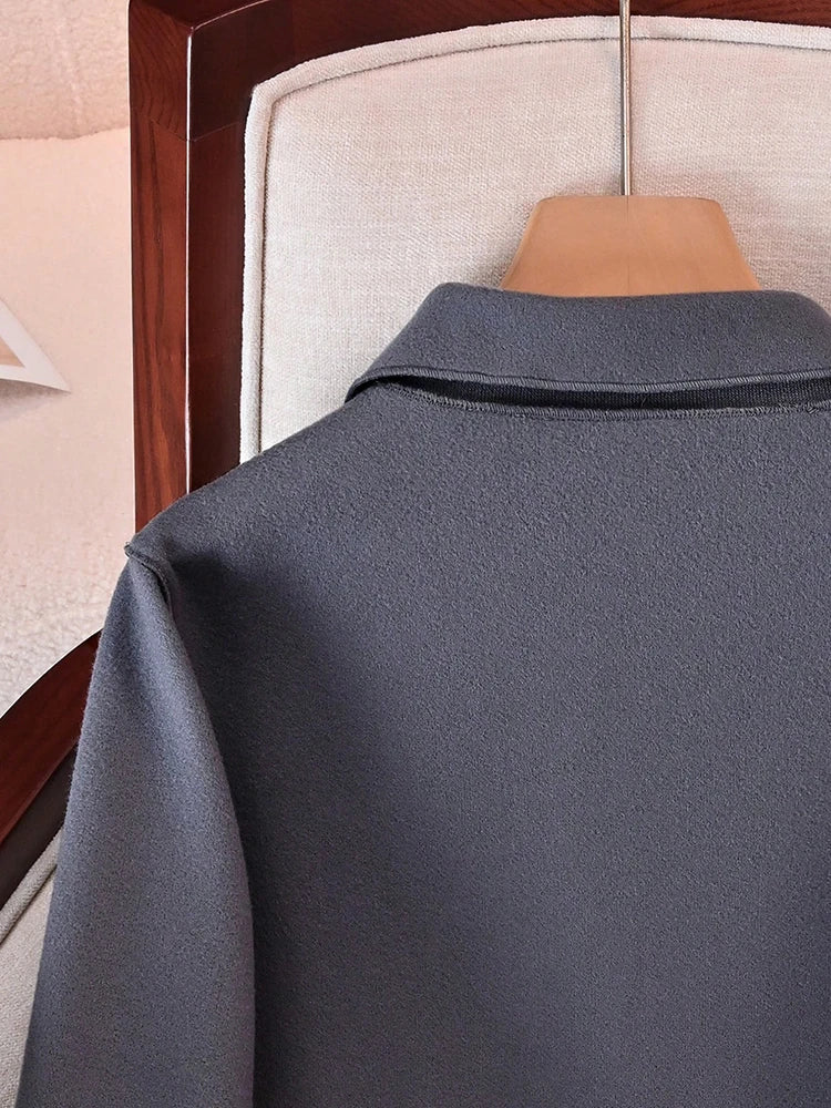Vue arrière d'un manteau à boutons en laine gris anthracite sur un cintre en bois.