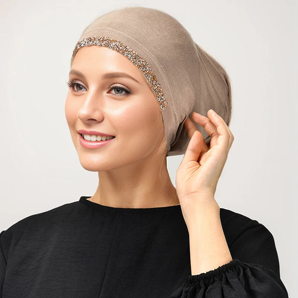 A woman wearing a beige elegant modal cotton stretchy inner hijab with gold sequin trim.
