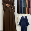 Ein Modell trägt ein langes, fließendes, offenes Abaya-Kaftan aus dunkelbranem Stoff.