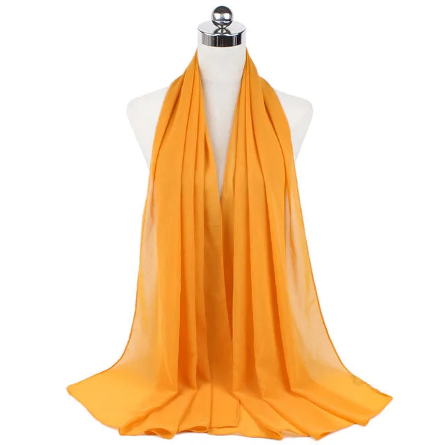 A bright orange chiffon hijab scarf draped around a mannequin's neck.