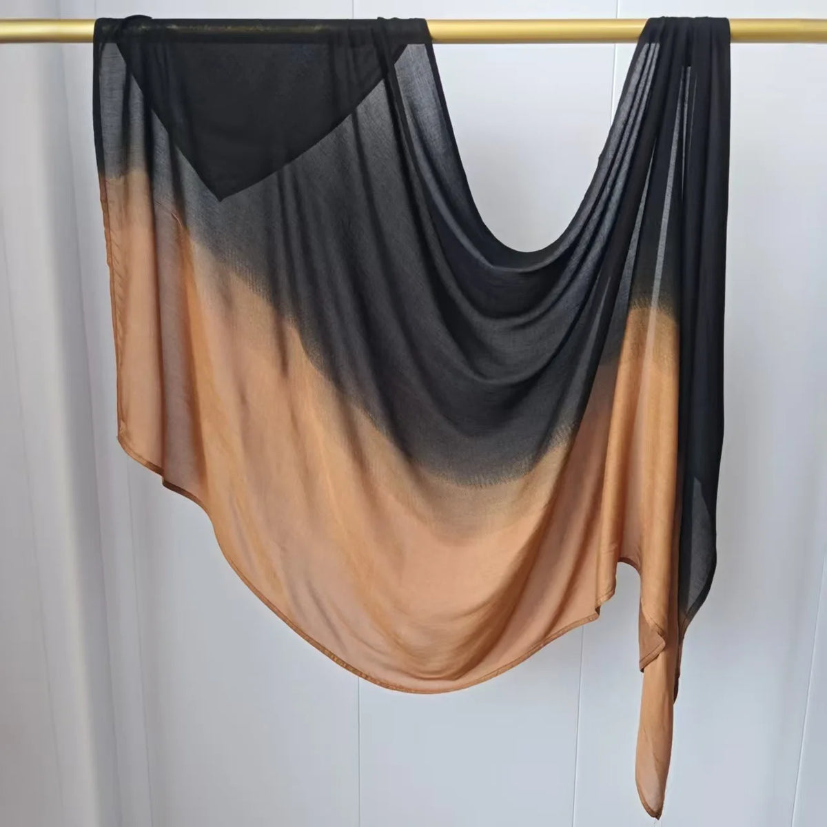 Pañuelo hijab de algodón rayón degradado negro y nude colgado en una cuerda de ropa.