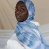 Una mujer vistiendo un pañuelo hijab con estampado acuarela azul y ropa blanca.