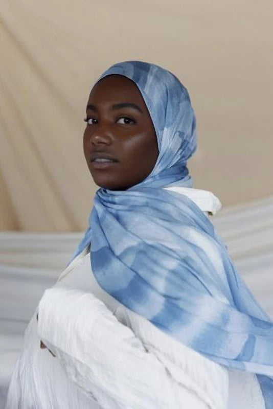 Una mujer vistiendo un pañuelo hijab de estampado de leopardo acuarela azul y ropa blanca.