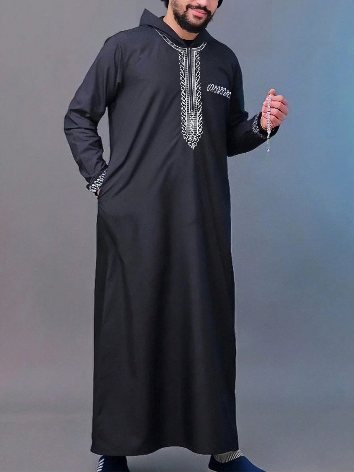 A man wearing a black Moroccan ethnic thobe with a stand collar and embroidery.
