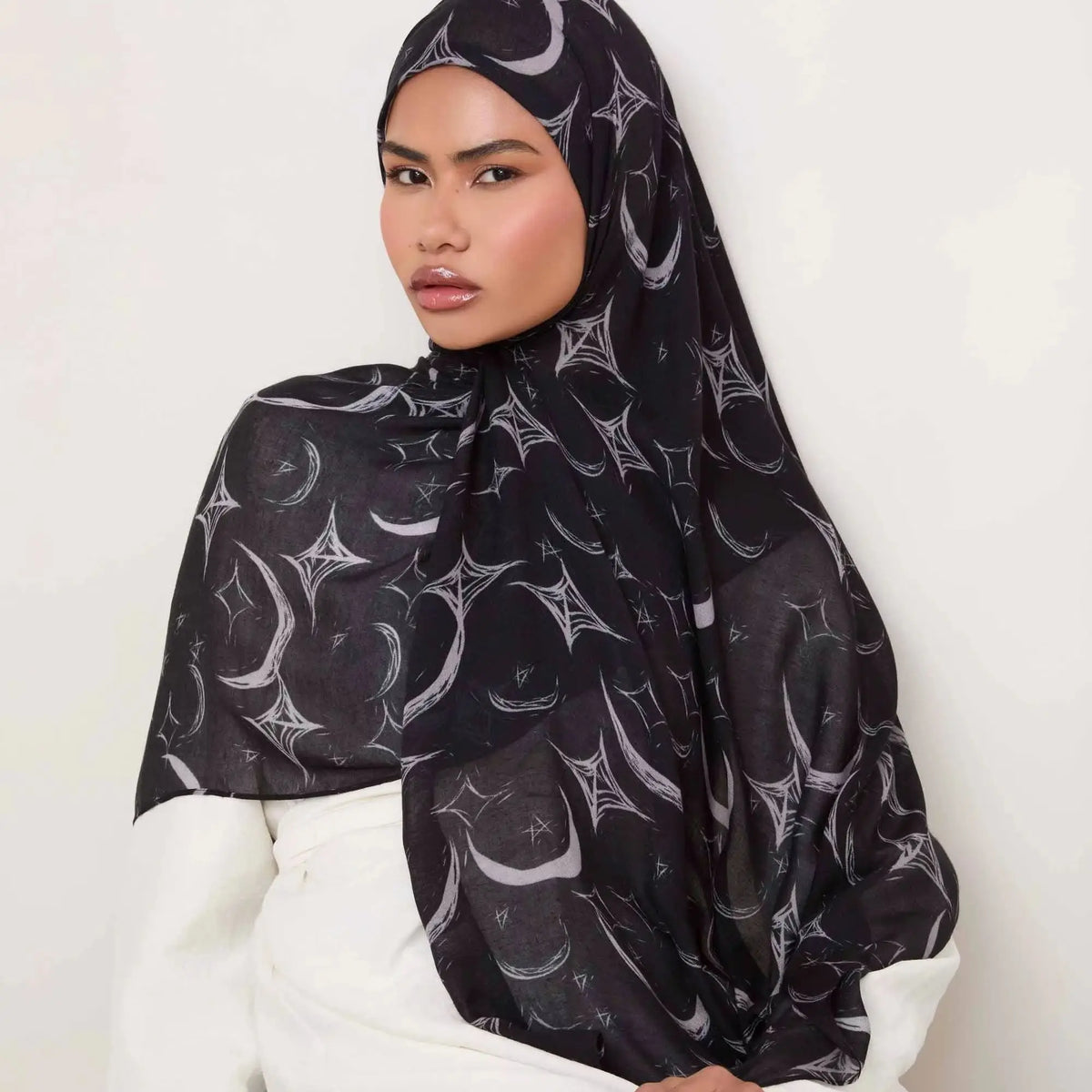 Une femme portant un foulard de coton à motifs floraux noirs avec des accents argentés.
