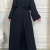 A woman wearing an elegant black abaya and kaftan set, shown from the front.
