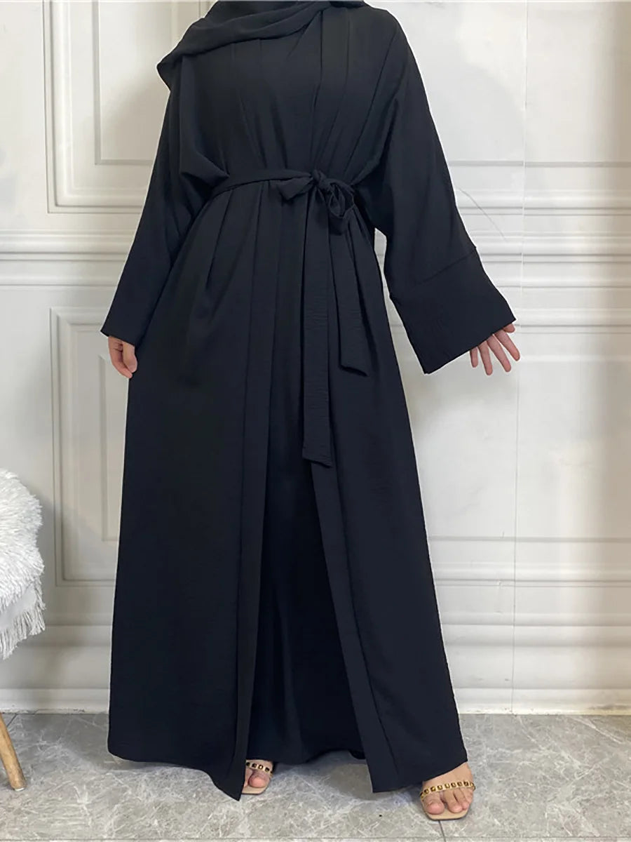 A woman wearing an elegant black abaya and kaftan set, shown from the front.