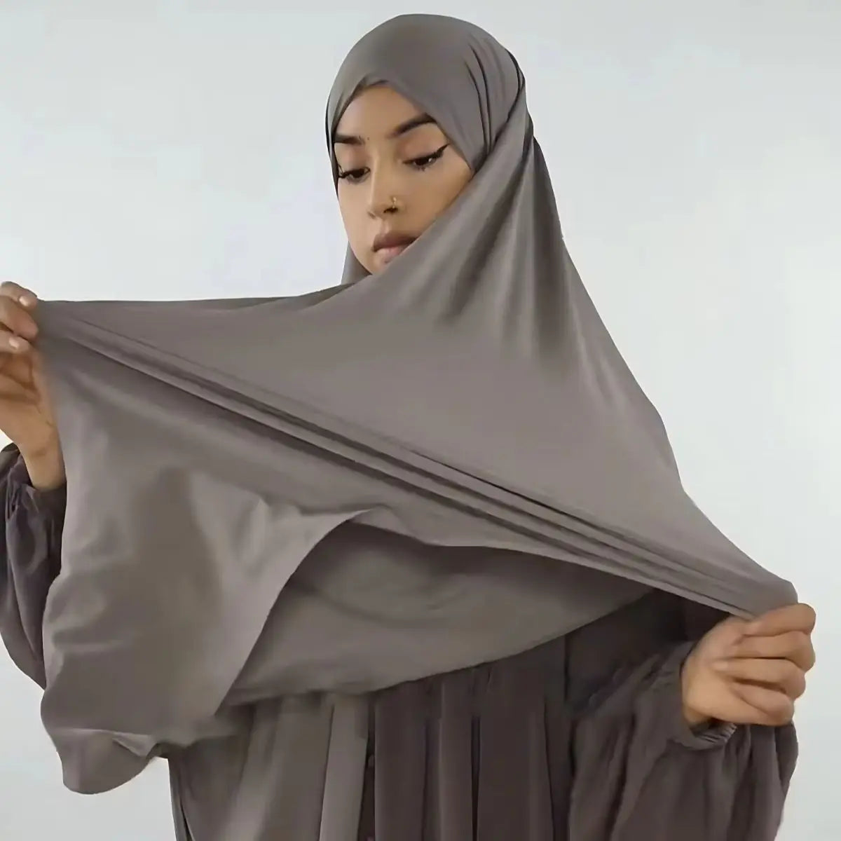 A woman wearing a large size stretchy modal square scarf for Islamic wear in a muted gray color.