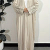 Beige lockere Kaftan-Abaya mit bestickten Ärmeln und weißem Hijab auf einem Hänger.