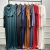Exposición de varias abayas y kaftanes islámicos largos y fluidos en tonos de verde, azul, marrón y rosa.