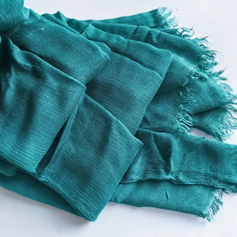 Une pile de foulards hijab en coton viscose vert-bleu avec pompons.