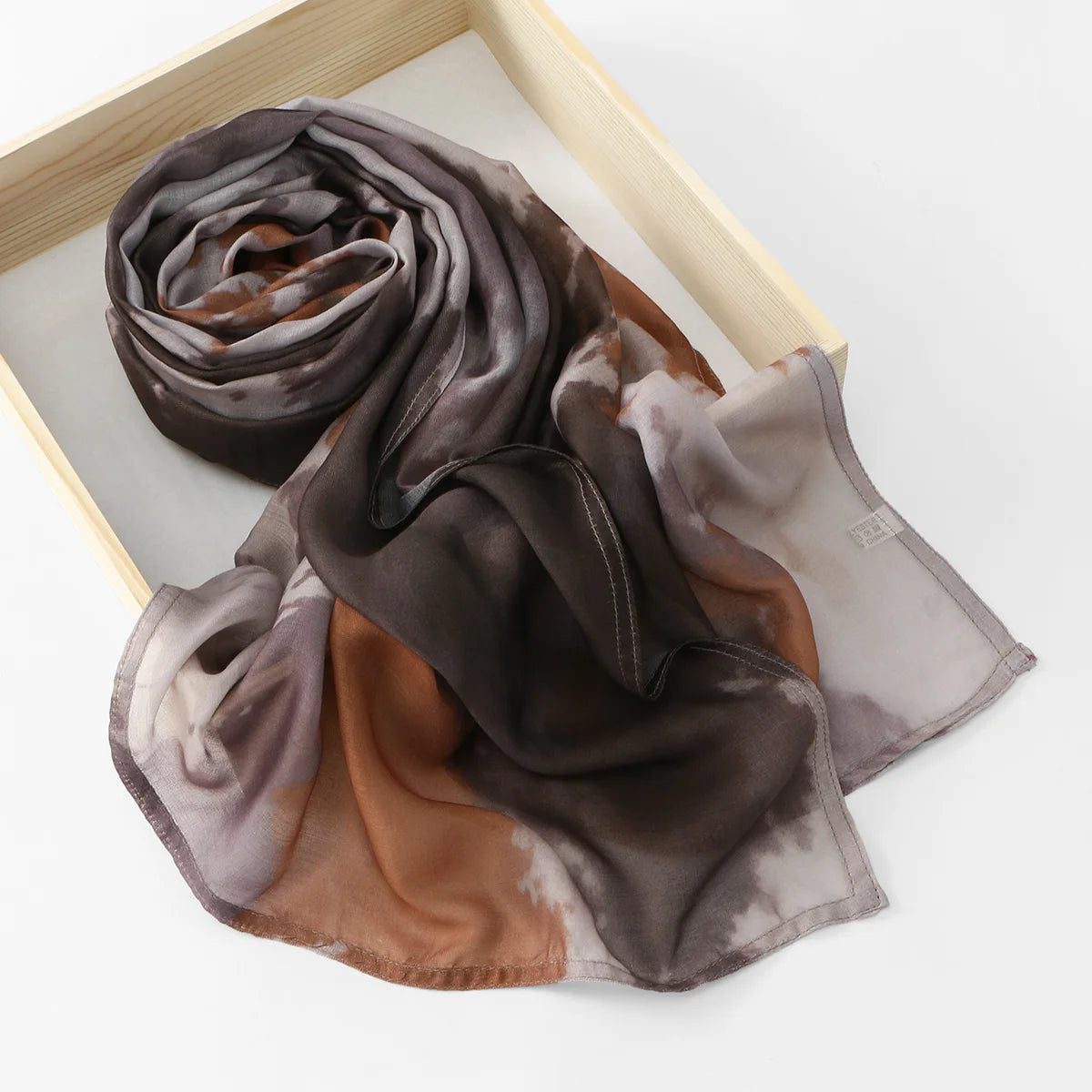 Écharpe hijab en coton à motif floral drapée dans des tons de brun et gris, présentée dans une boîte en bois.