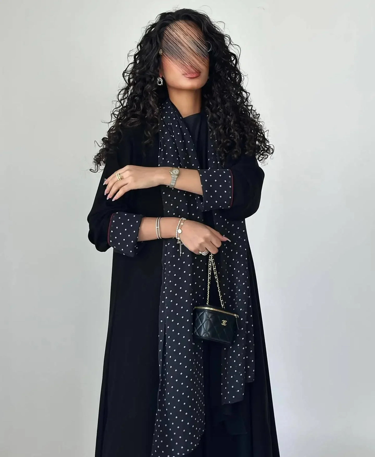 Eine Frau trägt ein elegantes schwarzes Polka-Dot-Abaya-Cardigan-Kleid mit langen Ärmeln und einem dunklen Oberteil.