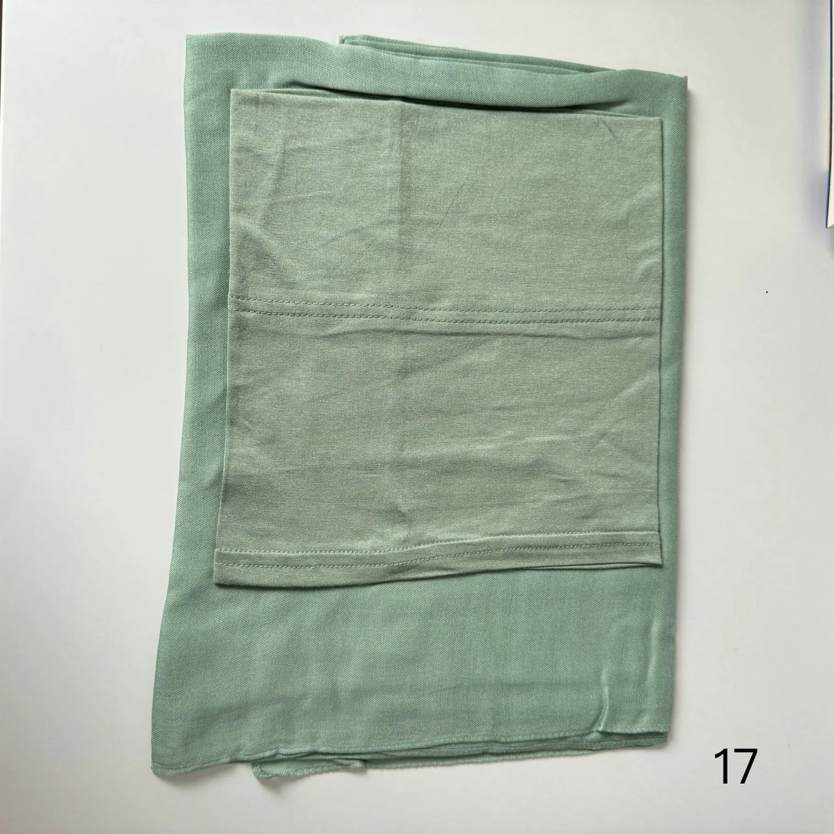 A light sage green soft modal rayon hijab set folded neatly.