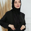Eine Frau trägt einen schwarzen Modal-Baumwoll-Jersey-Hijabschal und schwarze Kleidung.