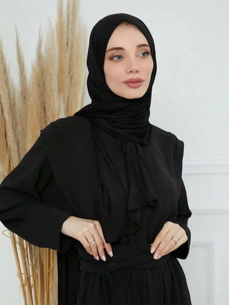 Eine Frau trägt einen schwarzen Modal-Baumwoll-Jersey-Hijabschal und schwarze Kleidung.