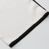 Una túnica blanca larga con ribetes y bordados negros.
