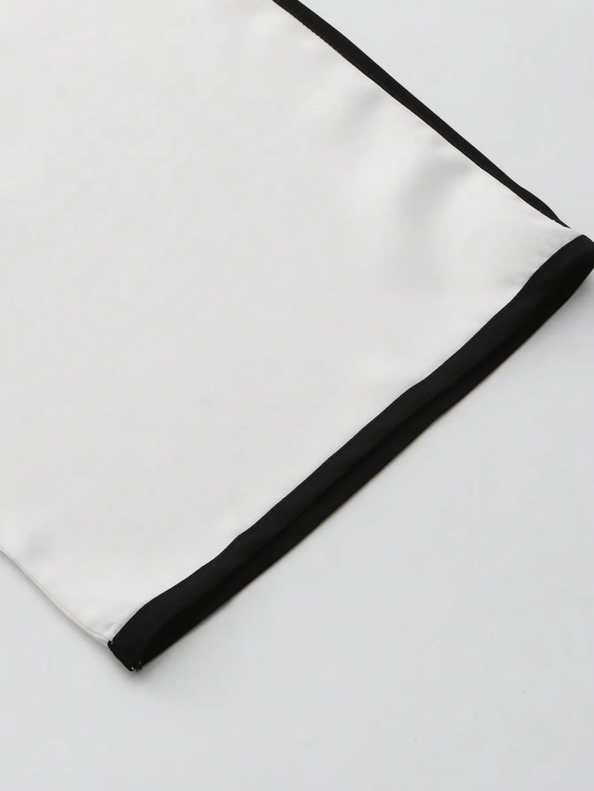 Una túnica blanca larga con ribetes y bordados negros.