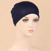A model wears a navy blue classic stretch jersey turban cap on her head.
