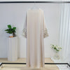 Beige bestickter lockerer Kaftan-Abaya an einem Haken vor weißem Hintergrund