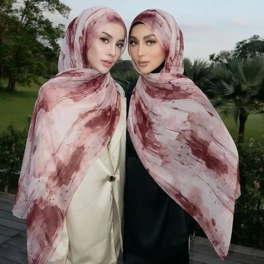 Dos mujeres vistiendo pañuelos de hijab de algodón viscosa estampados en rosa y marrón, de pie al aire libre
