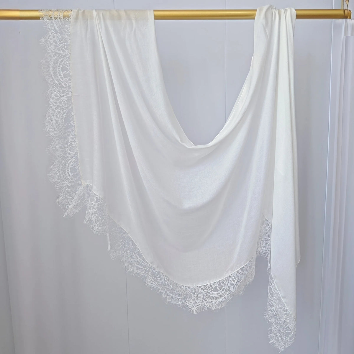 Hijab de gasa blanca con estampado doble, drapeado sobre un perchero de madera.