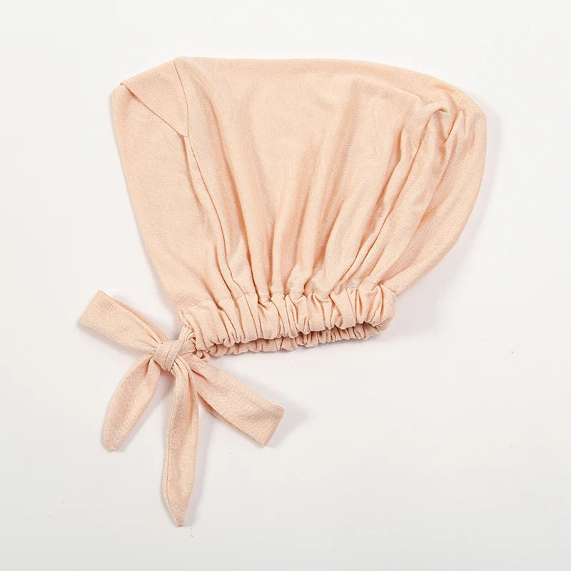 A light peach colored adjustable cotton jersey inner hijab cap tied with a bow.