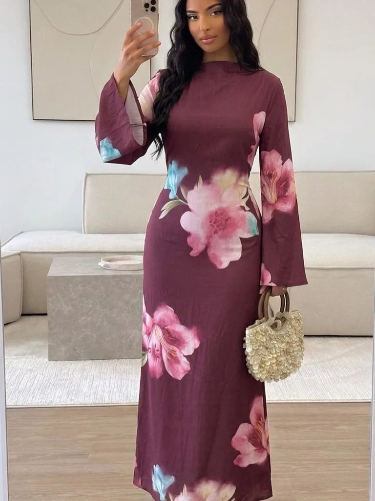 Model trägt ein langes, dunkles Pflaumen-Abaya-Kleid mit rosa und blauen Blumenmustern drinnen.