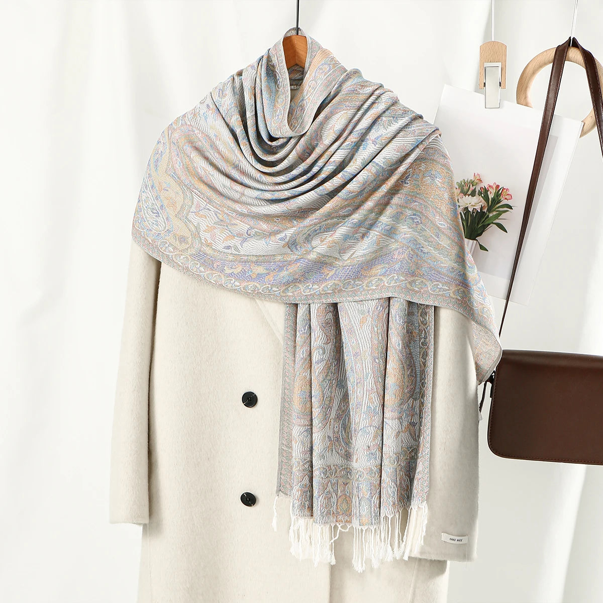 Abrigo beige con un chal bordado tipo paisley azul claro y beige sobre el cuello.