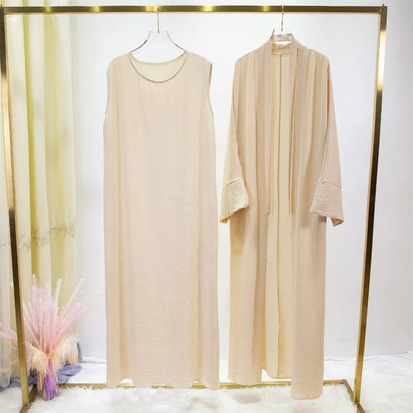 A beige two-piece Muslim jilbab set for women displayed on a gold hanger against a white background.