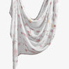 Un foulard hijab blanc doux et fluide avec un imprimé floral de fleurs roses et jaunes.