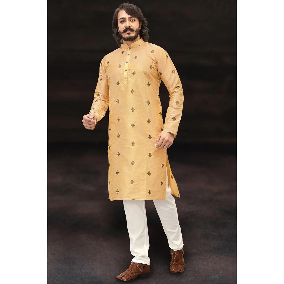 Un hombre vistiendo un jubba thobe tradicional beige claro con bordado dorado y pantalones blancos.