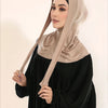Una mujer vistiendo un hijab beige de cobertura total con un lazo sobre un vestido negro.