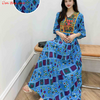 Eine Frau modelliert ein blaues Boho-besticktes Maxi-Kleid mit farbenfrohen Blumenmustern.