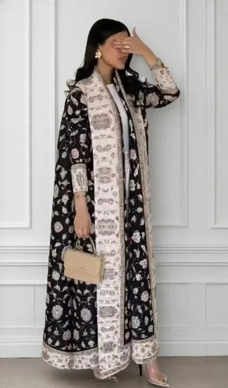 Una mujer modela un cárdigan abrigo abaya plisado negro y blanco con detalles dorados.