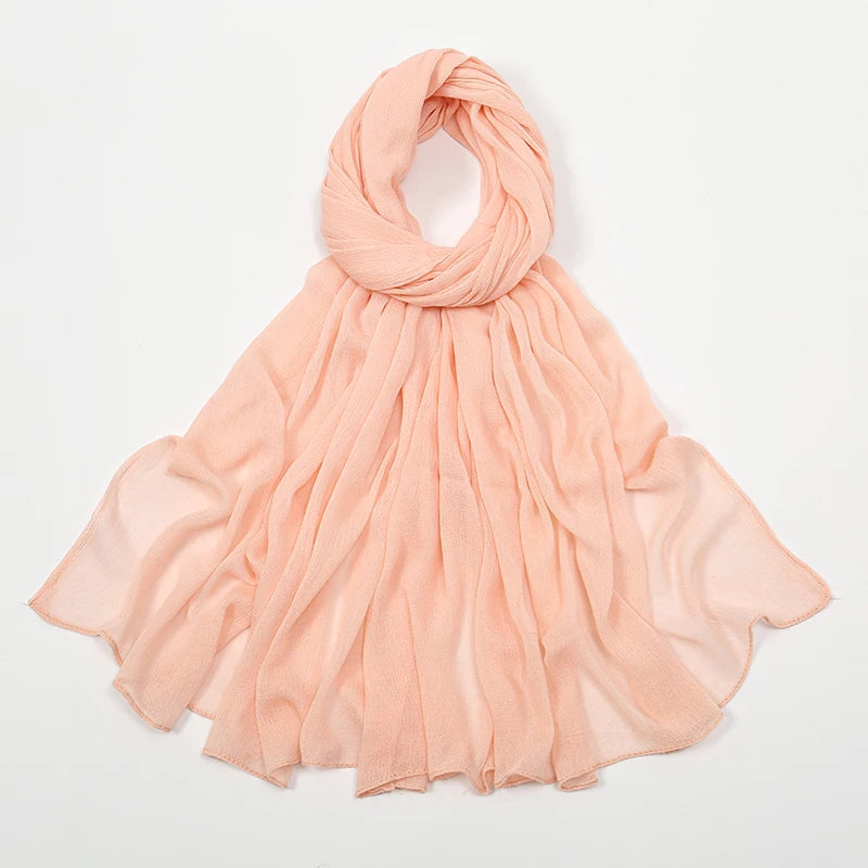 Écharpe volantée en rayon couleur pêche, nouée et drapée sur fond blanc.