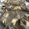 Nahaufnahme von beigem Crinkle-Satin-Chiffon-Stoff, der drapiert und gefaltet ist, zeigt seine Textur und den Fall.