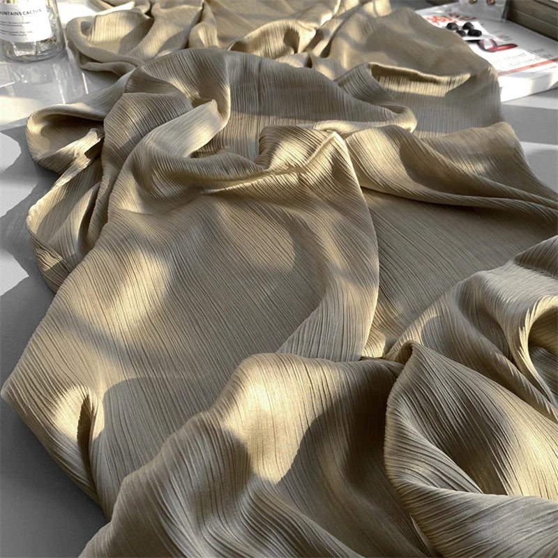 Nahaufnahme von beigem Crinkle-Satin-Chiffon-Stoff, der drapiert und gefaltet ist, zeigt seine Textur und den Fall.