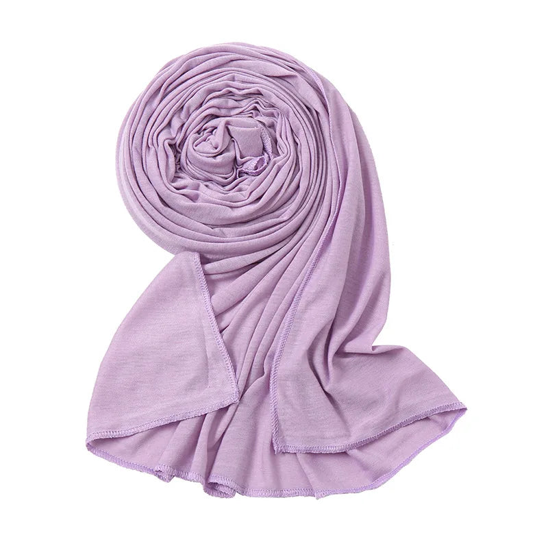 Ein helllila, schlichtes Baumwoll-Jersey-Schal, aufgerollt in einer Spirale.