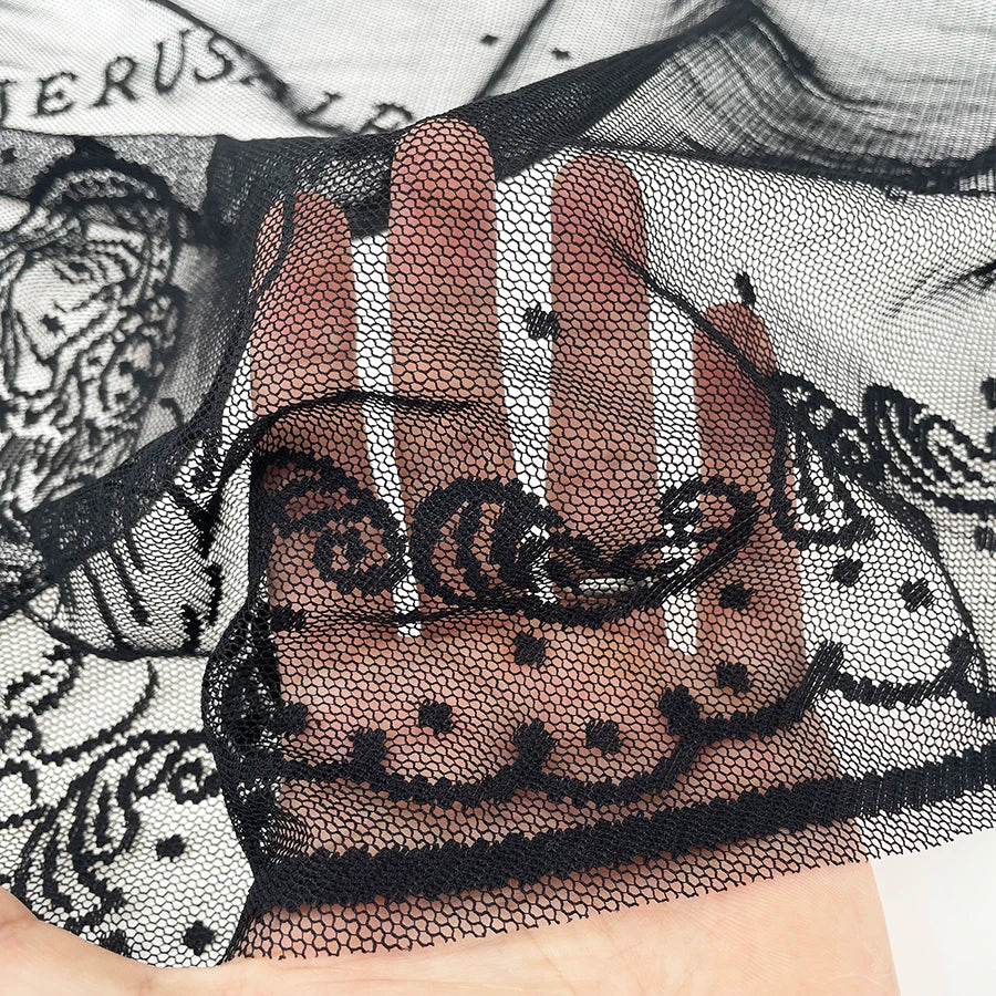 Tela negra transparente con bordado intrincado de una imagen de la Madonna y el Niño en una mano.