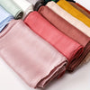 Ein Stapel aus rosa, beige und gelben Satin-Crinkle-Hijab-Schals für Frauen.