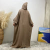 Une abaya marron à portée complète avec capuche et manches batwing, présentée contre un mur blanc.