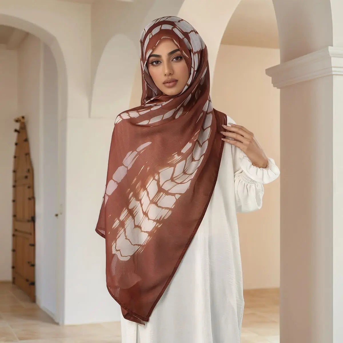 Eine Frau trägt einen braunen Aquarell-Digitaldruck-Hijab und weiße Kleidung.