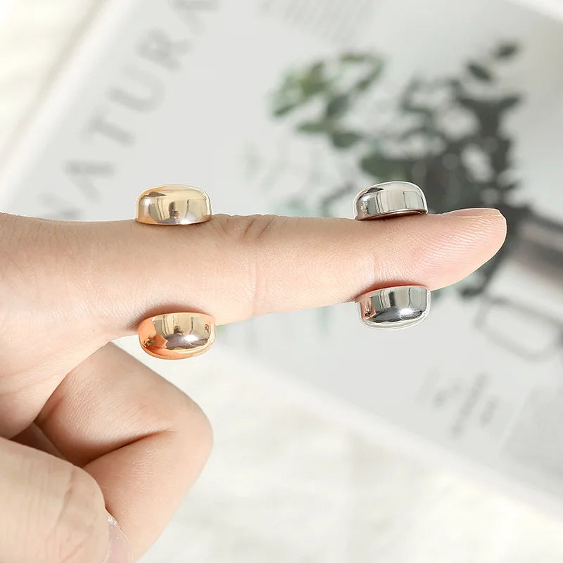 A hand holds a set of two gold and silver macaron brooches for hijab clips.