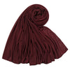 Un foulard hijab en jersey de coton marron foncé roulé et drapé, montrant des plis doux.