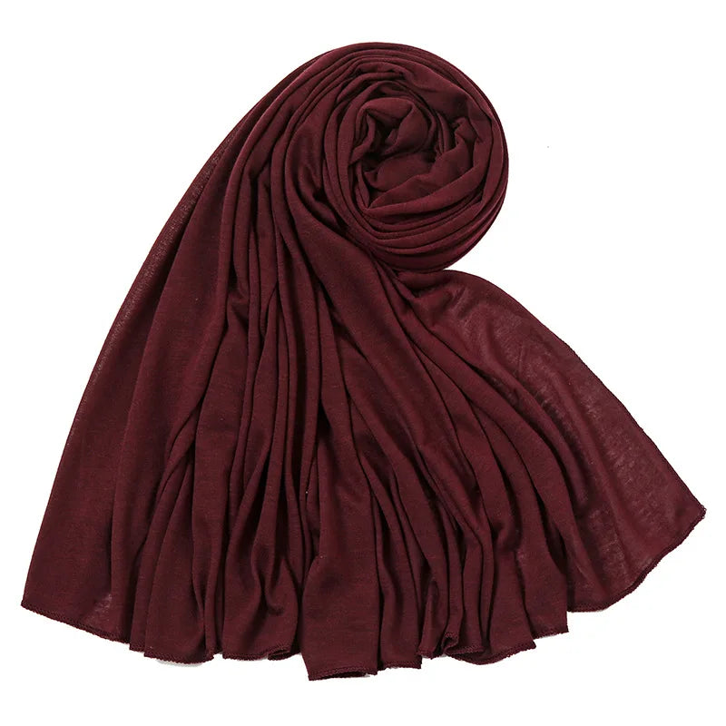 Un foulard hijab en jersey de coton marron foncé roulé et drapé, montrant des plis doux.